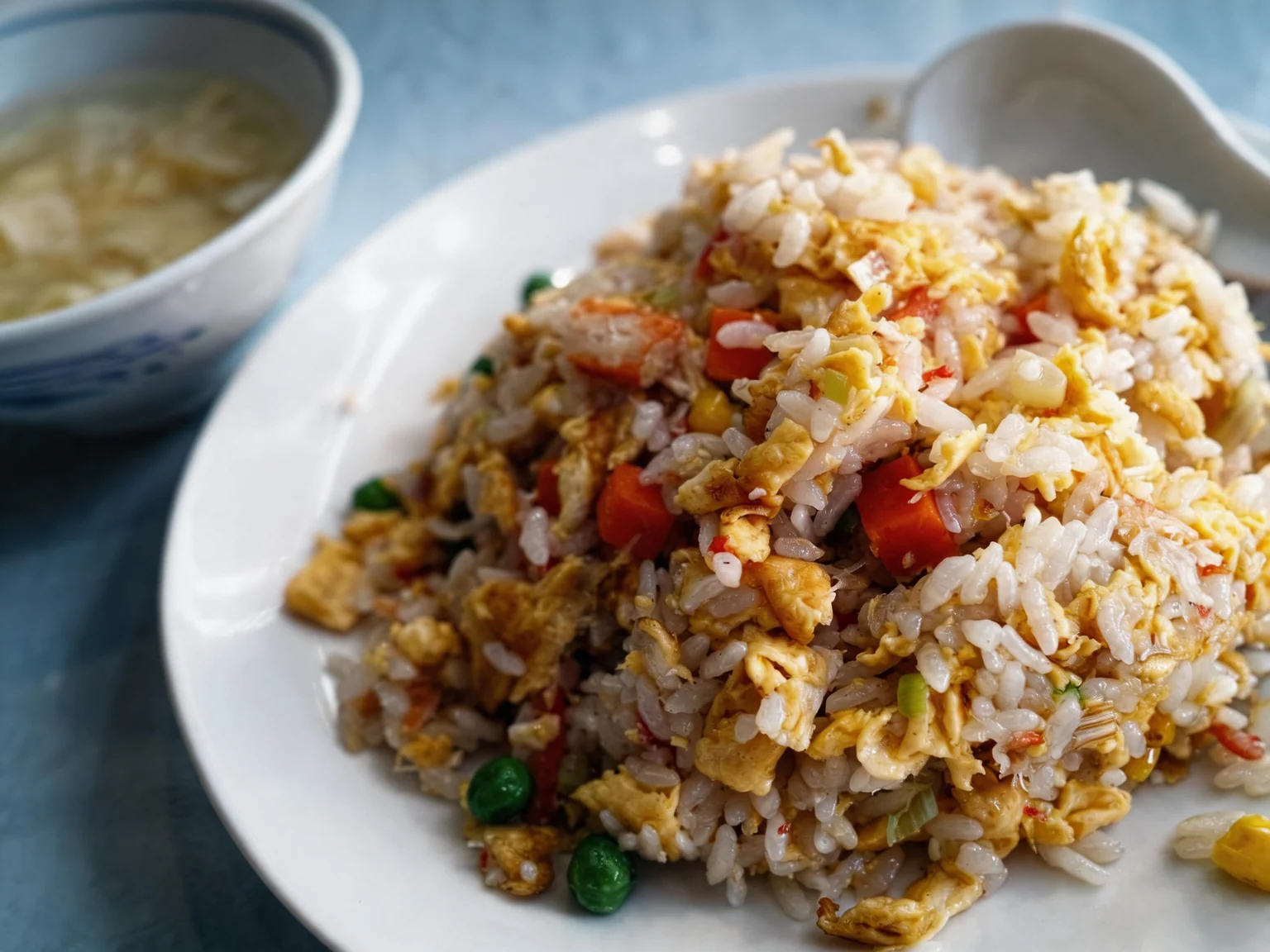 Riz cantonnais. Sur une assiette blanche, un bol à côté.
